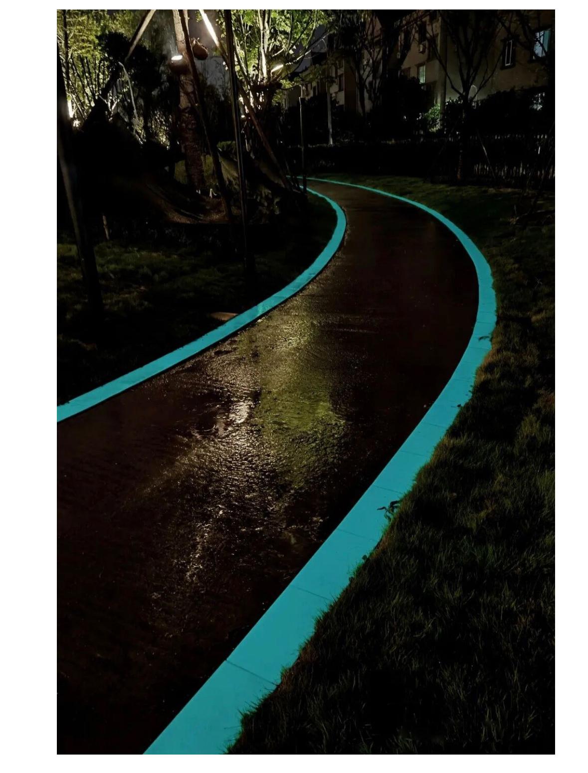 Même allée de parc la nuit — bordures en pierre lumineuse turquoise qui balisent tout le tracé sinueux